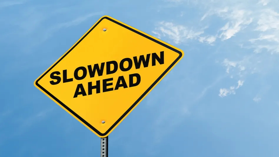 A yellow diamond traffic sign reads Slowdown ahead in black capital letters in front of a blue sky.