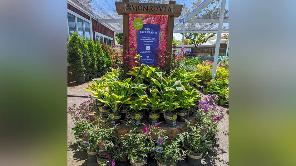 A circular wooden display that says Monrovia at the top shows several plants in green Monrovia buckets.