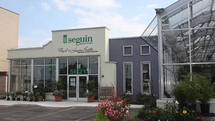 Exterior of a gray building with a sign that reads "Seguin" in green.